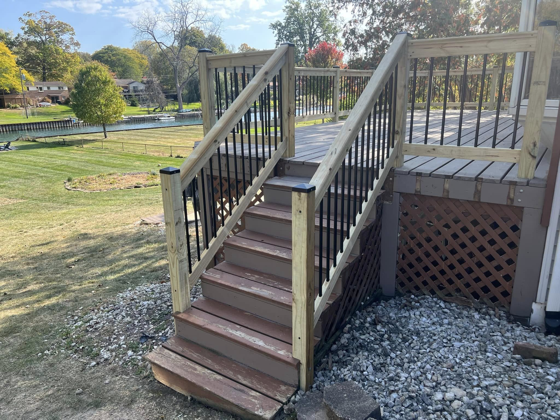 Worker installing wooden deck boards on a raised porch with tools scattered nearby. Person working on a wooden deck with tools and boards in a construction site.
