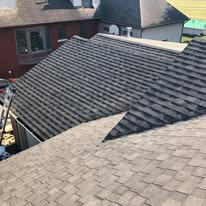 Roof ridge with tools and supplies laid out on shingles at sunset Two tool bags on a shingled roof ridge at sunset, with trees in the background