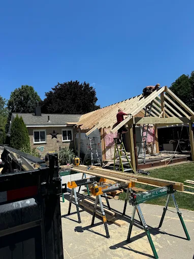 Severely damaged roof and gutters with debris along a house exterior after a storm