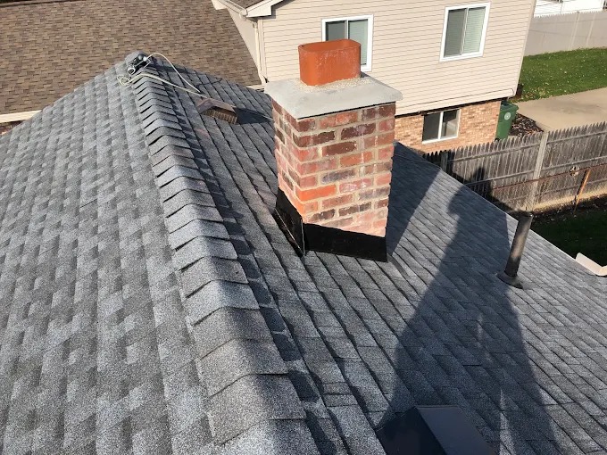 Roofing tools and plans on a shingled rooftop, with a neighborhood view in the background Roof inspection tools on a shingled rooftop with a clipboard, overlooking a suburban neighborhood