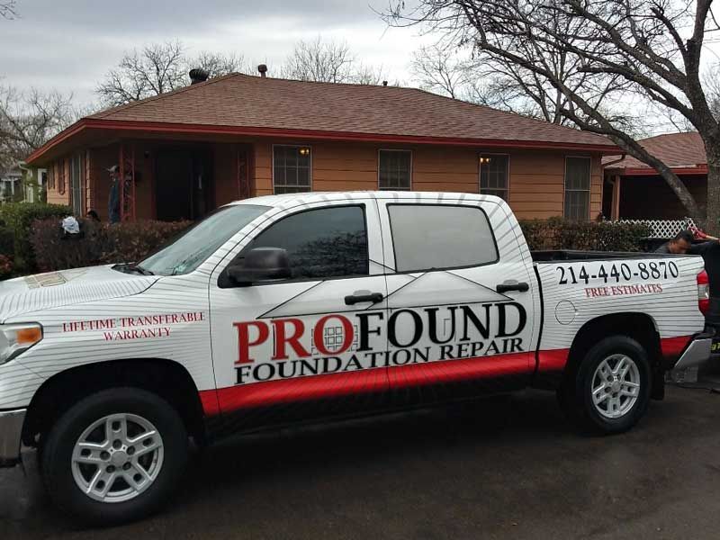 White ProFound Foundation Repair pickup truck parked in front of a brick house on a rainy street
