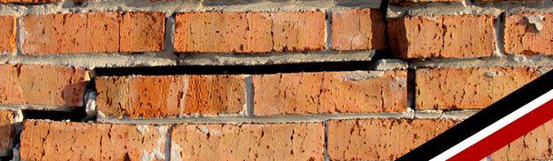 Orange brick wall with horizontal cracks and a red, white, and black diagonal stripe in the corner