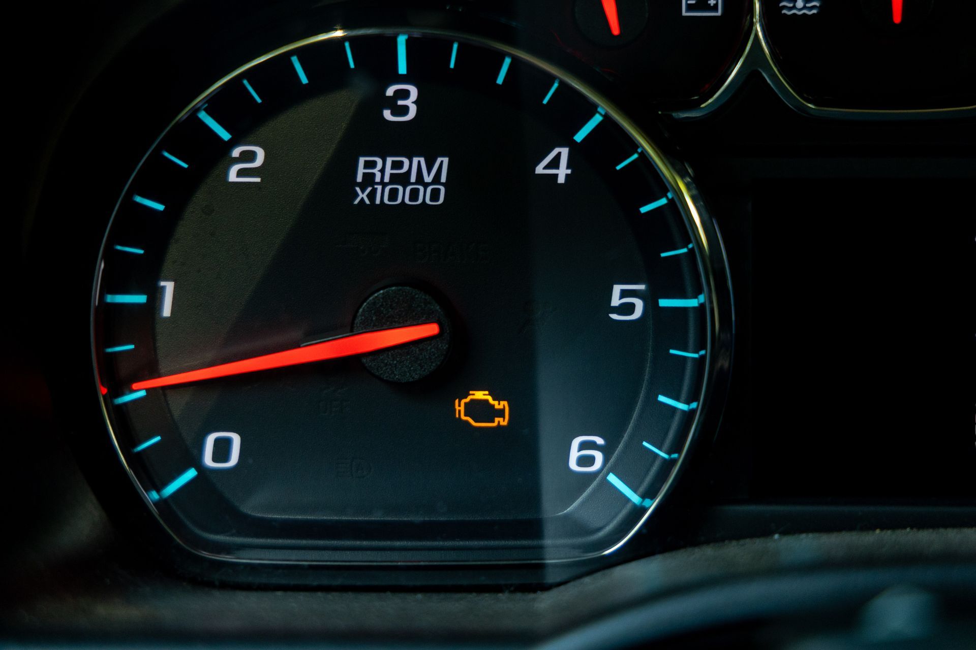 Car dashboard tachometer with red needle near 1,000 RPM and a lit check engine warning light Car dashboard tachometer with red needle near 1,000 RPM and a lit check engine warning light