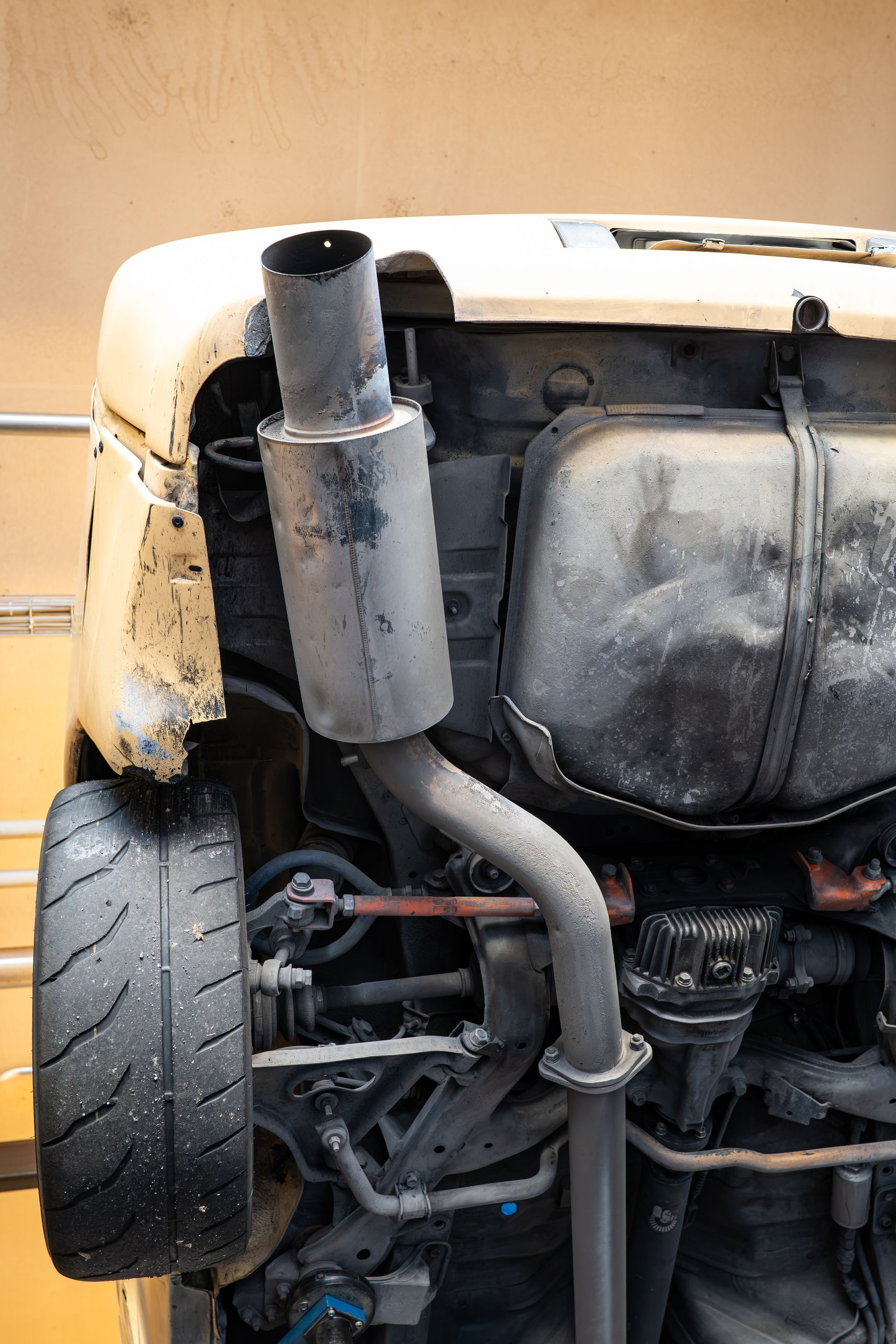 Damaged car front end with exposed engine, exhaust pipe, and wheel. Damaged car front end with exposed engine, exhaust pipe, and wheel.