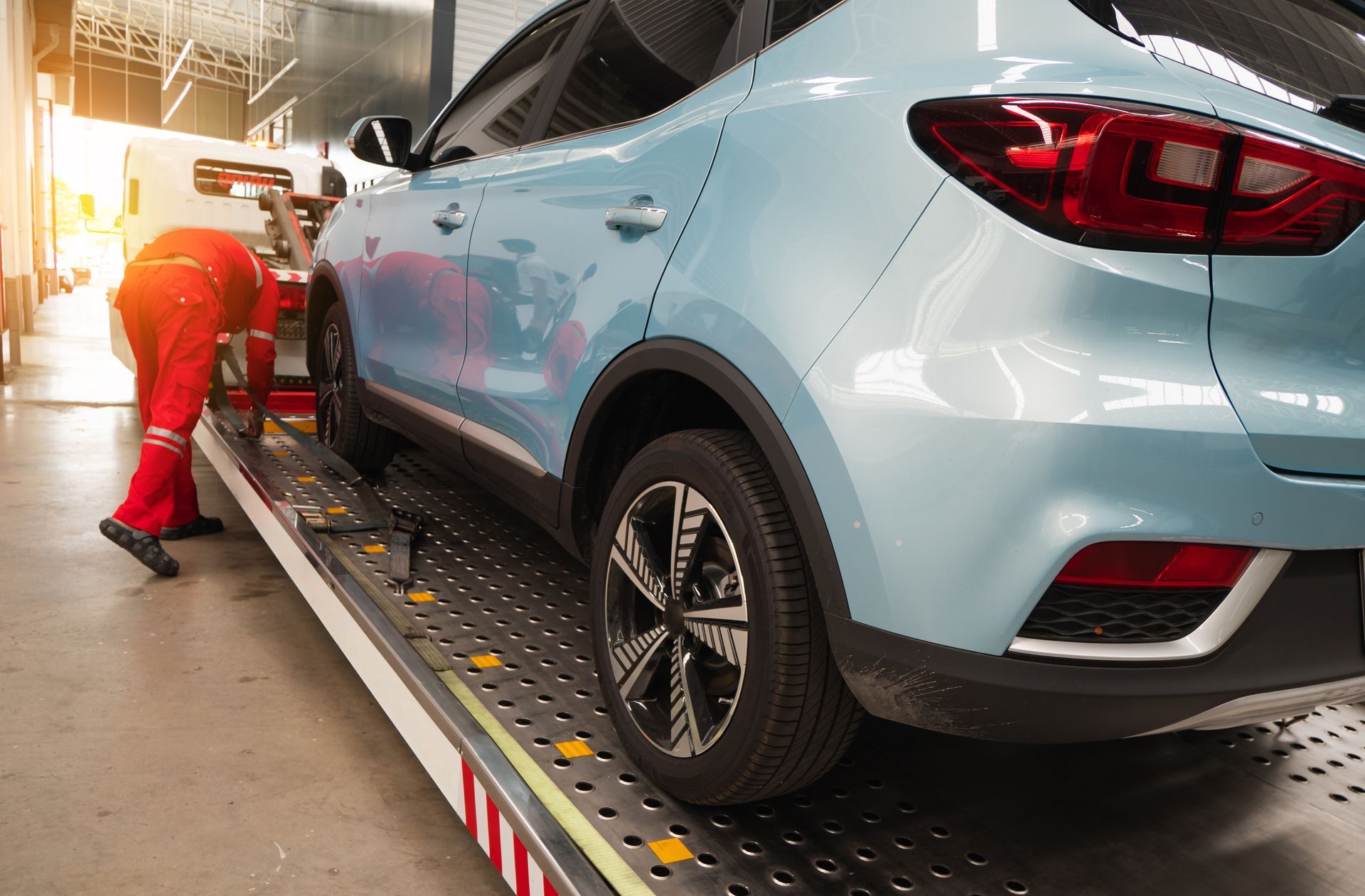 Worker inspecting a light blue SUV on an assembly line under bright factory lights Worker inspecting a light blue SUV on an assembly line under bright factory lights
