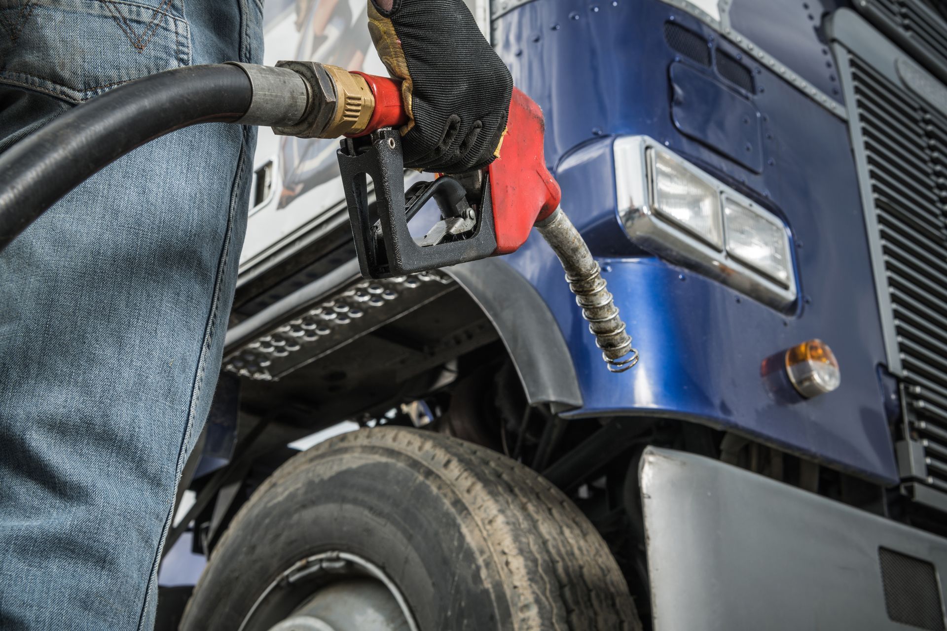 Fuel nozzle filling a blue truck at a gas station close-up