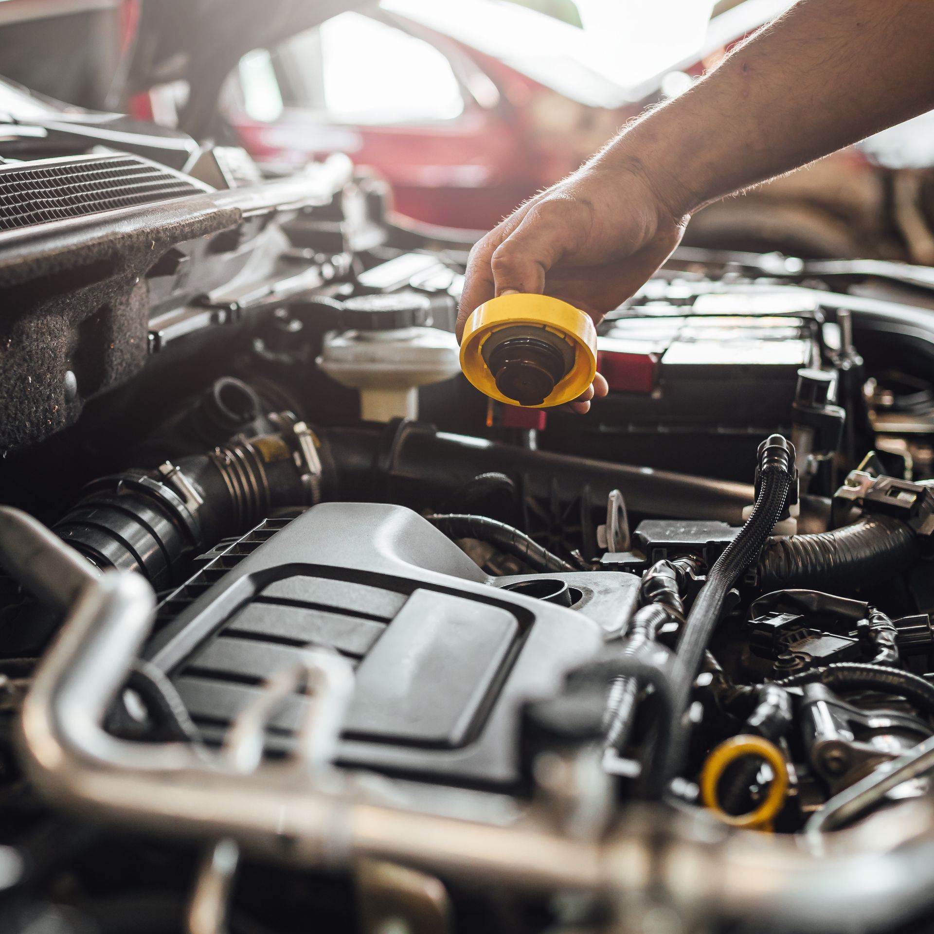 Mechanic pouring yellow oil into a car engine under the hood