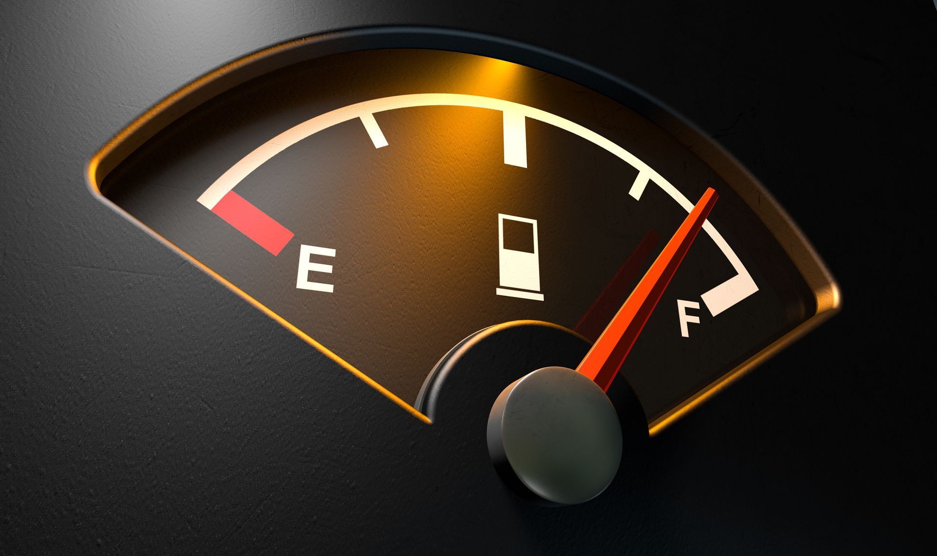 Fuel gauge with needle near full, showing low-to-high markings on a dark dashboard.