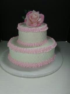 Two-tiered cake with light green frosting and pink trim, topped with a pink rose.