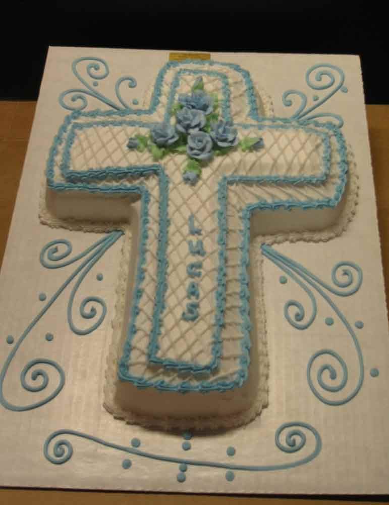 Cross-shaped cake decorated with blue frosting, a floral design, and the name 
