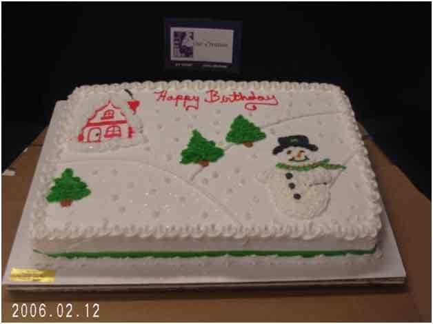 Rectangular cake decorated with a winter scene: snowman, trees, a house, and 