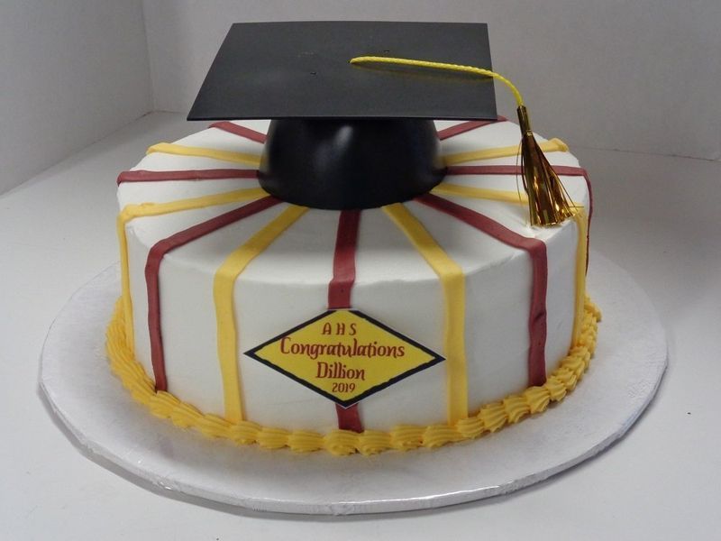 Graduation cake with black mortarboard, decorated with red and yellow stripes.