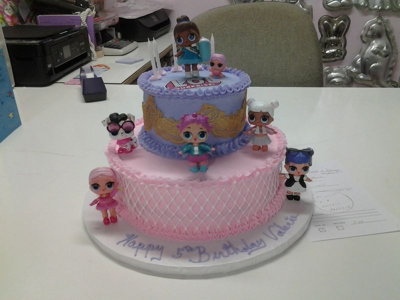 Two-tiered birthday cake decorated with pink and purple frosting, LOL Surprise dolls, and 