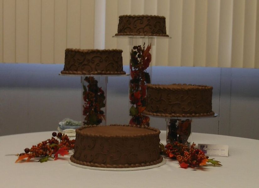 Chocolate cakes on tiered stands, decorated table with fall foliage.