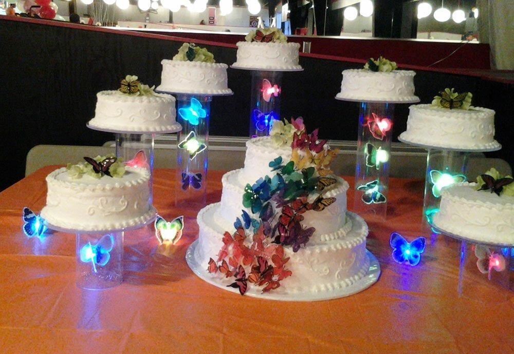 Wedding cakes with butterfly decorations on a table with lights.