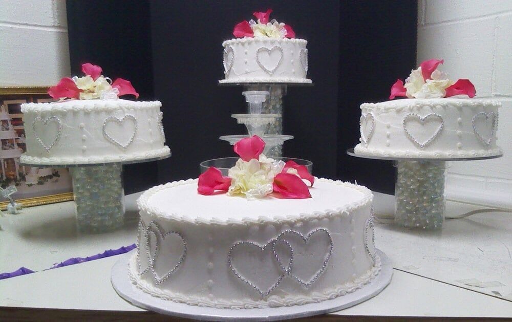 Wedding cakes: four white tiers with heart accents, decorated with pink and white flowers.