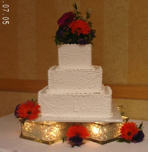 Three-tiered white wedding cake with flowers, 