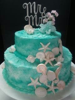 Two-tiered teal wedding cake decorated with seashells, starfish, and a 