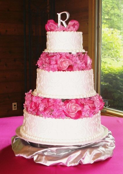 Five-tiered wedding cake, white frosting with pink flowers, topped with 
