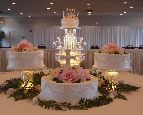 Wedding cakes: tiered white cakes decorated with pink flowers on a table in a banquet hall.