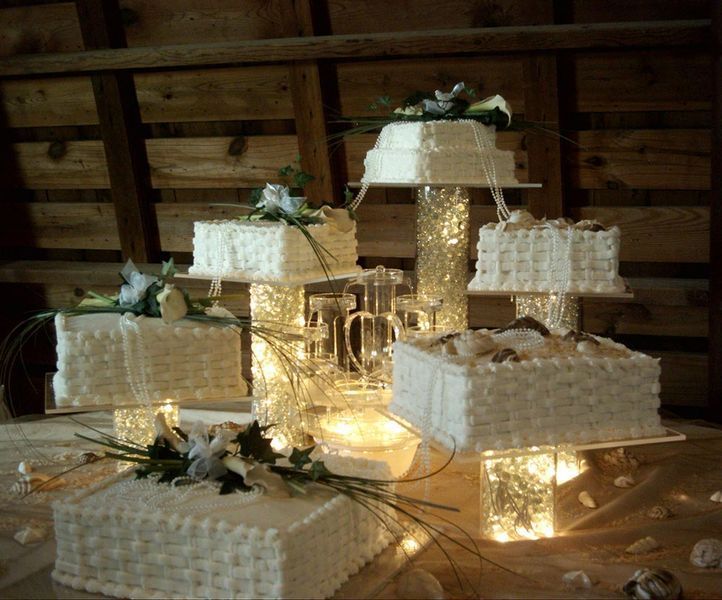 Multi-tiered wedding cake display with white frosting, flowers, and candles.