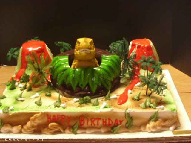 Dinosaur-themed birthday cake with volcano, palm trees, and 