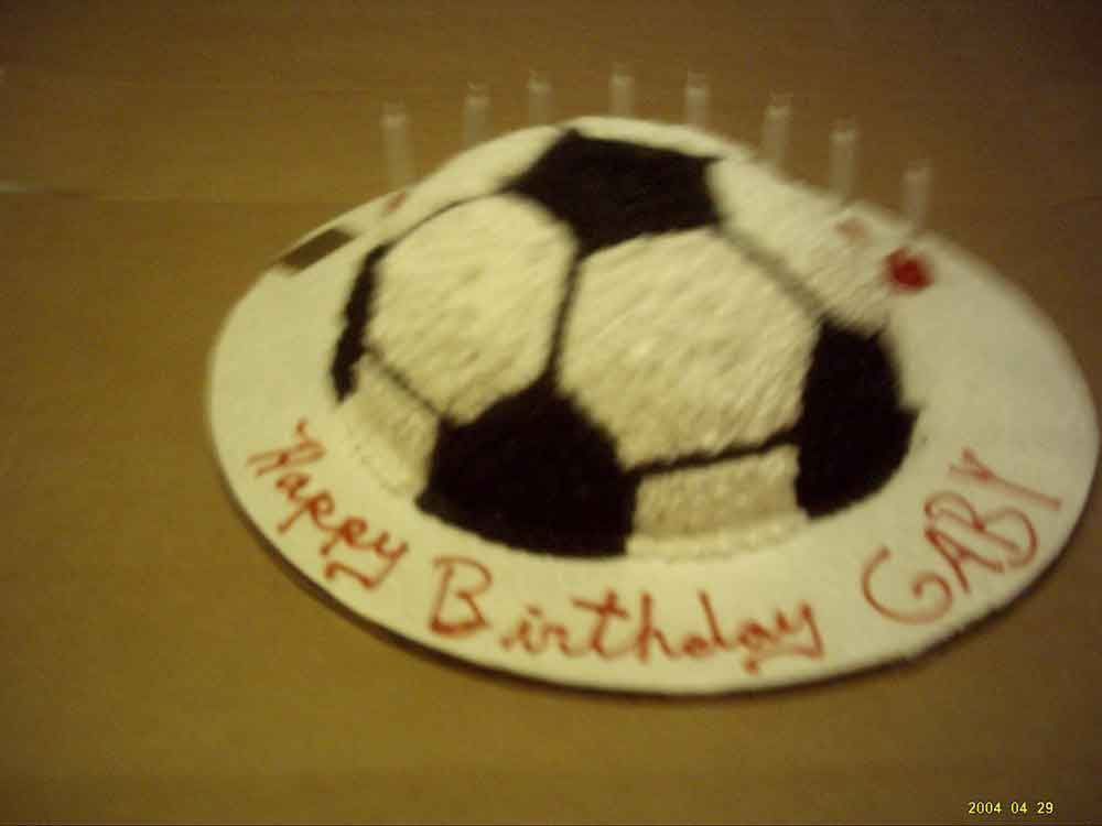 Soccer ball birthday cake, white frosting with black pentagons, red 