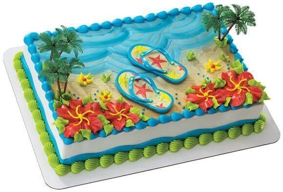 Beach-themed cake with blue ocean, sand, flip-flops, palm trees, and hibiscus flowers.
