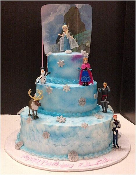 Three-tiered Frozen-themed birthday cake with figurines of Elsa, Anna, Olaf, Kristoff, and Sven; ice blue frosting.