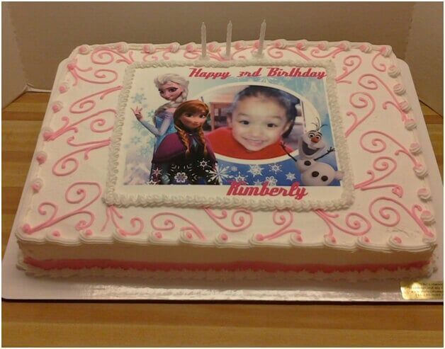 Birthday cake with a Frozen theme and a photo of a child.