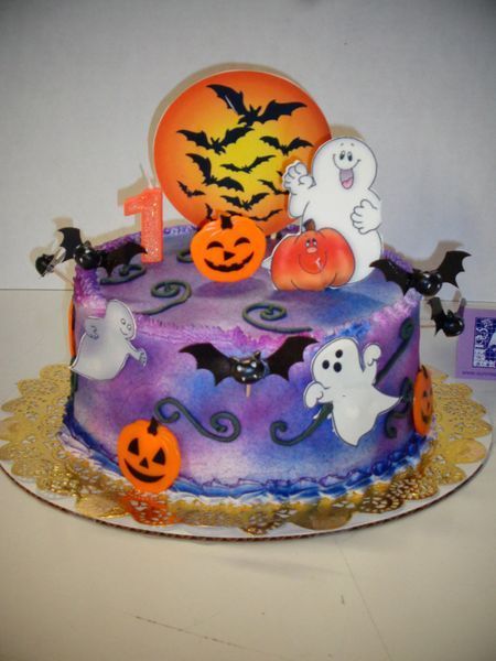 Halloween-themed cake with orange pumpkins, bats, ghosts, and a full moon with a number 