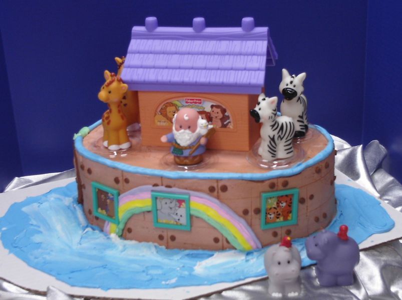 Noah's Ark cake with Fisher-Price toys: giraffe, zebras, elephant, and hippo with blue icing for water.