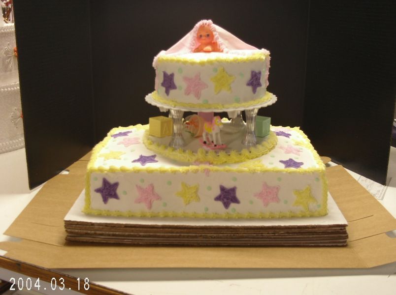 Baby shower cake with two tiers, star decorations, and a carousel design.