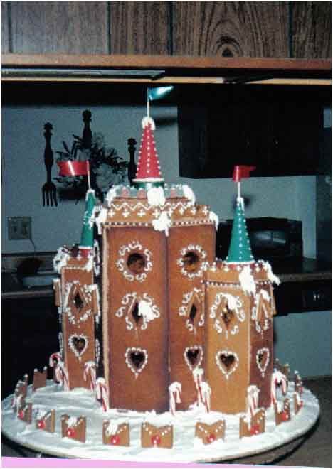 Gingerbread castle with decorative towers, candy cane accents, and flags, on a white plate.