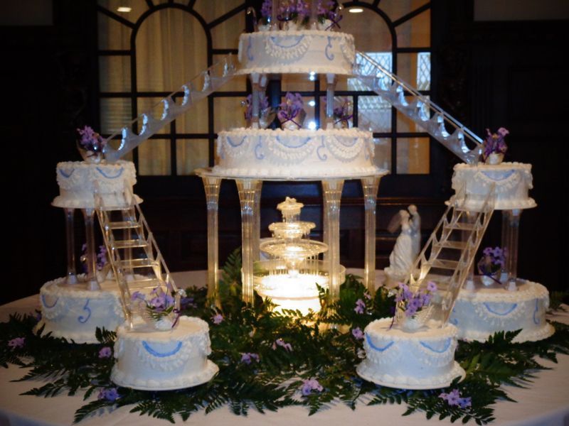 Wedding cake with multiple tiers and levels connected by clear stair-like structures.