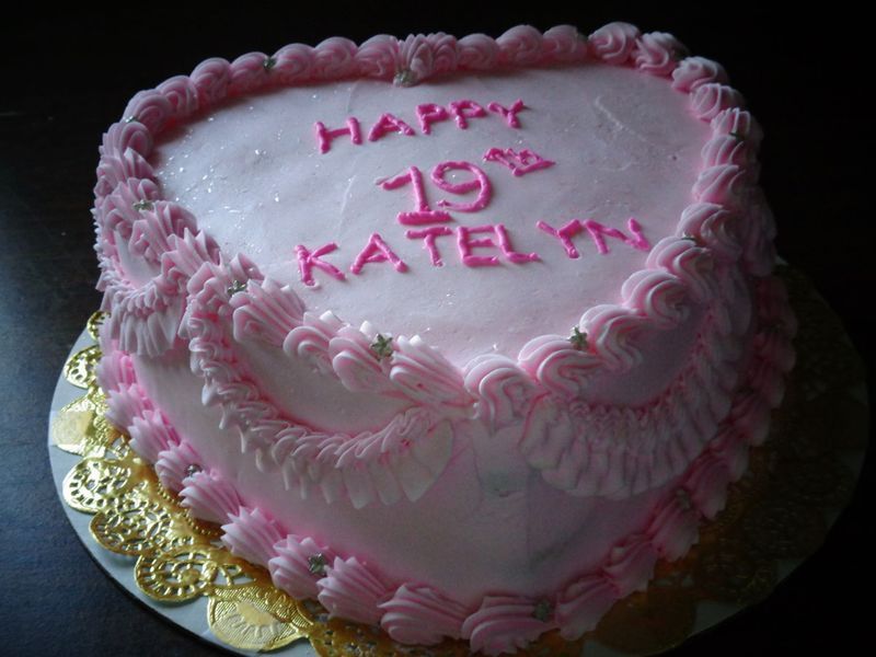 Pink heart-shaped cake decorated with frosting and the words 