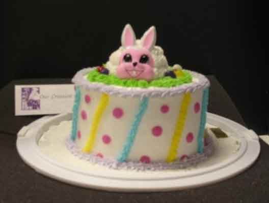 Easter cake with a bunny on top, polka dots, and stripes; set on a white plate.
