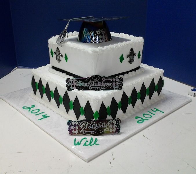 Two-tiered graduation cake with black and green diamond pattern. Topped with a mortarboard and 