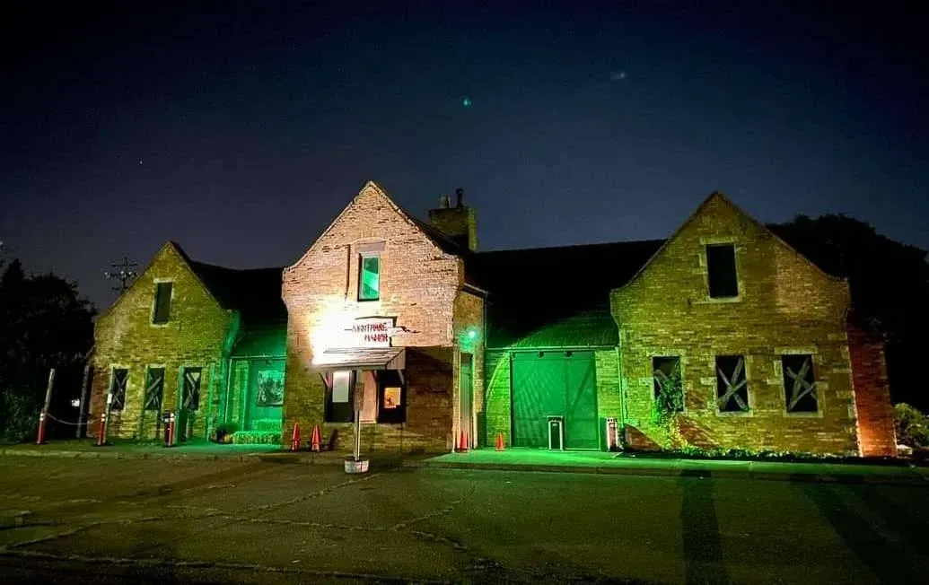 Lit stone building at night with green and white lights on the facade