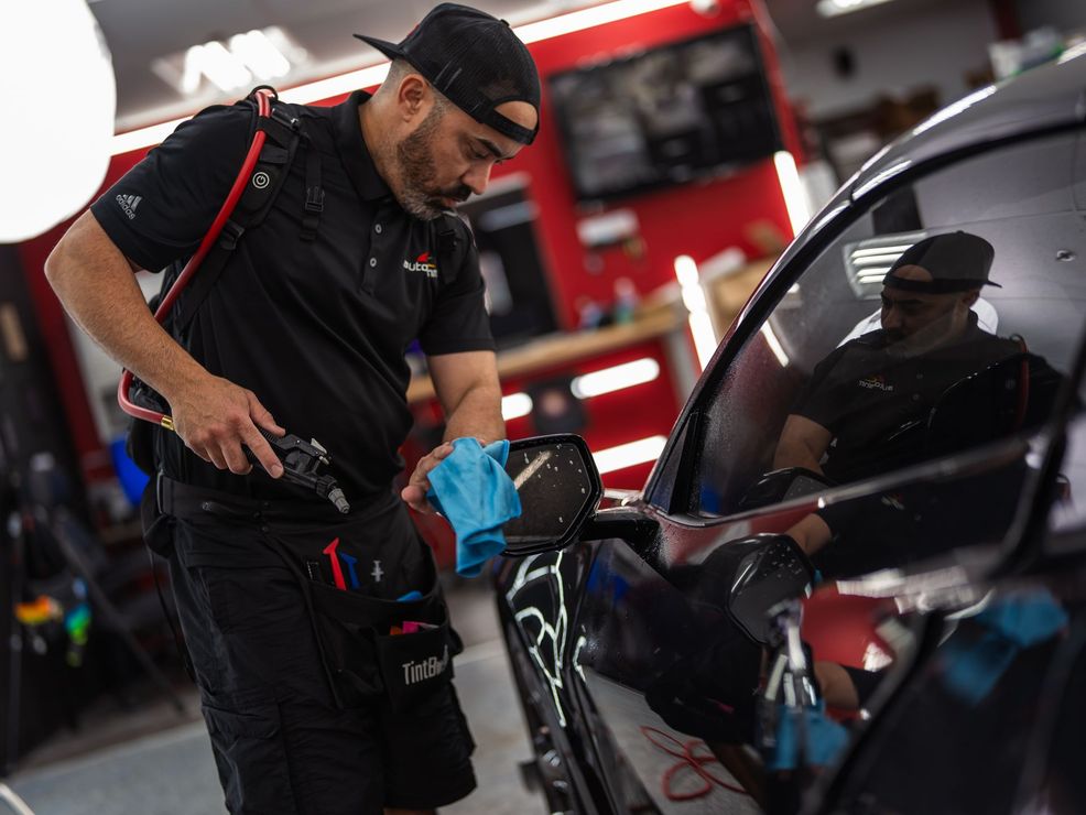 A man is cleaning a car with a towel in a garage.
