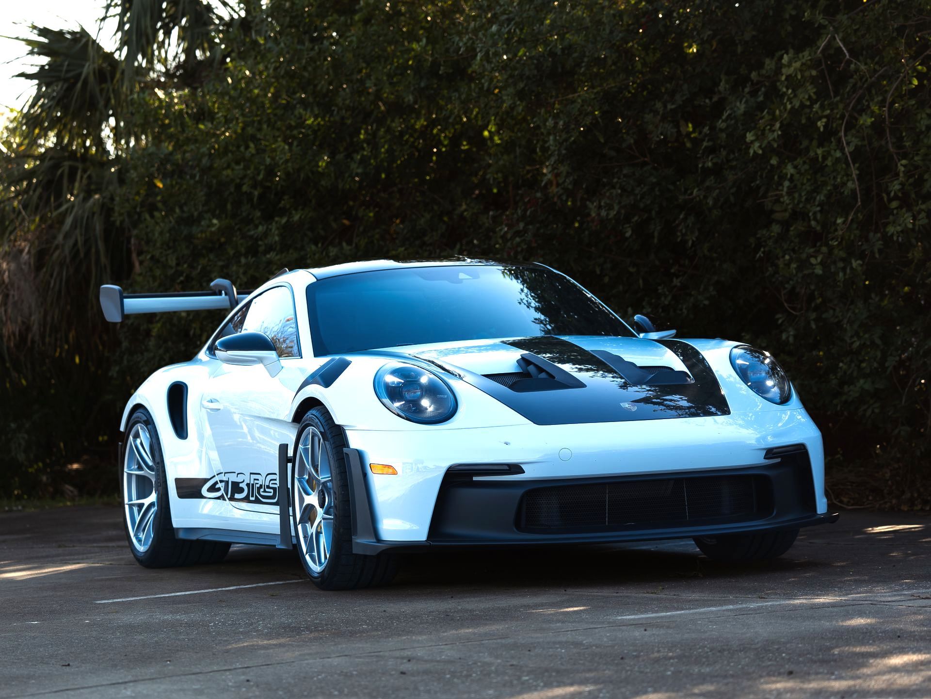 A white porsche 911 gt3 rs is parked on the side of the road