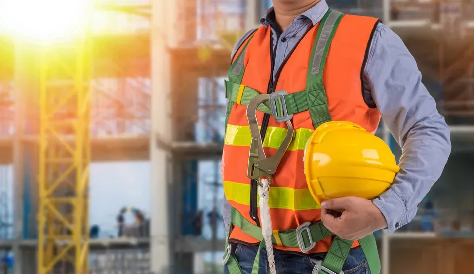 anonymous worker holding a hardhat wearing an orange vest