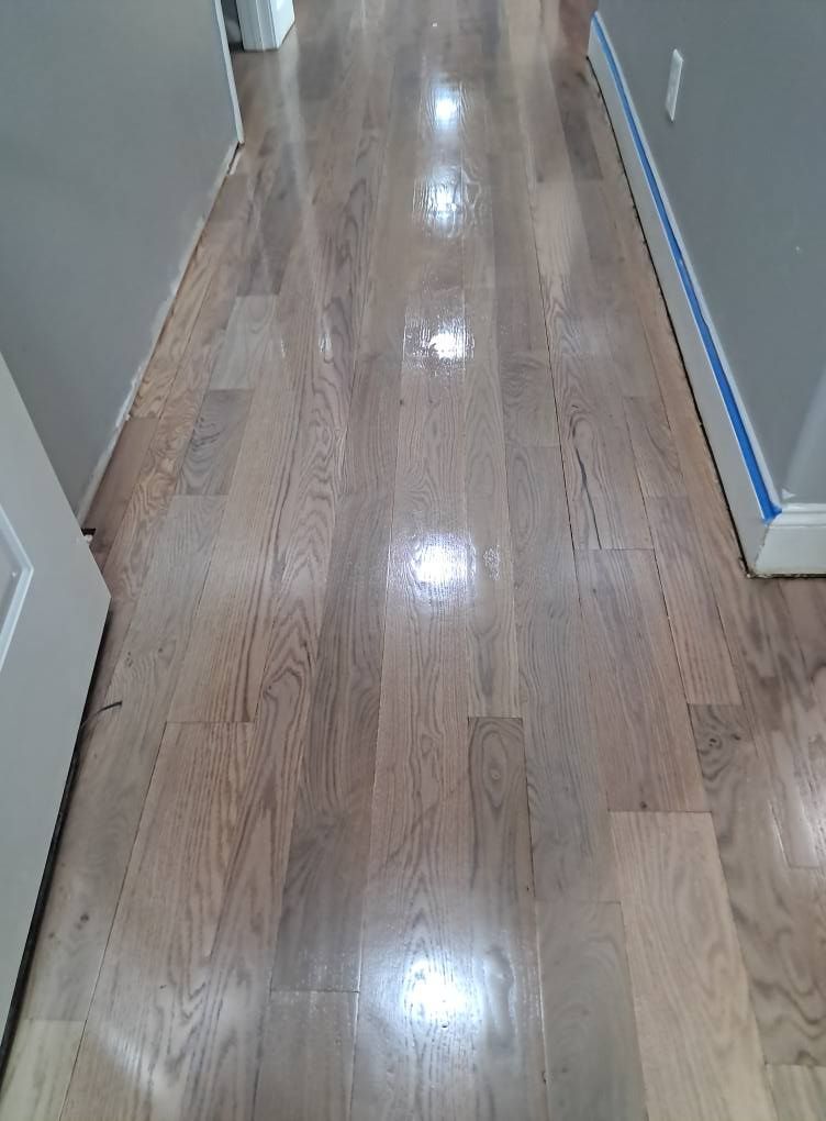 A hallway with hardwood floors and a blue tape on the wall