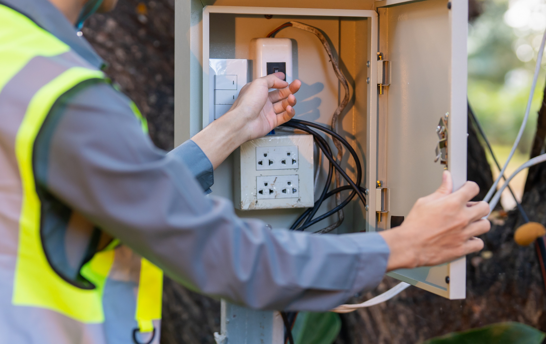 Worker installing wiring in an open electrical box outdoors