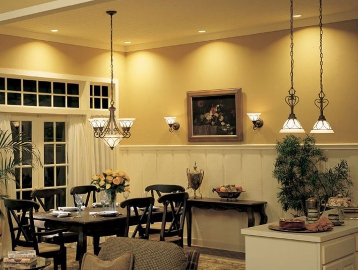 Warm, elegant dining room with hanging chandeliers, dark wood table, and floral centerpiece