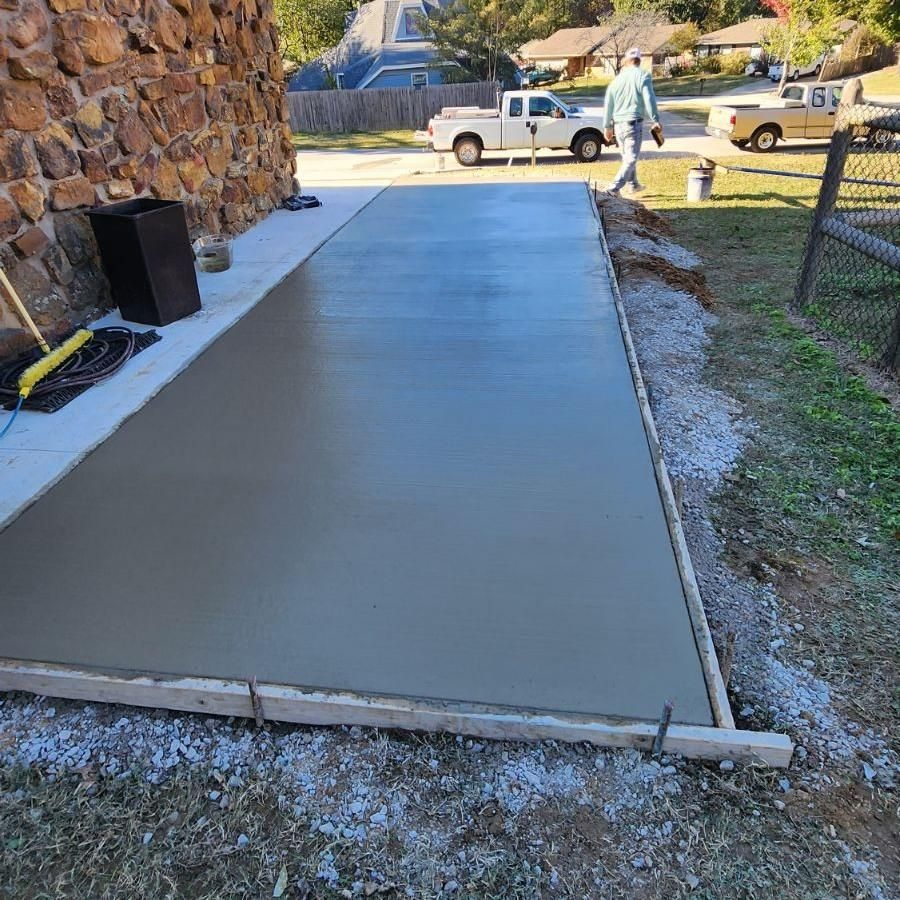 A concrete driveway is being built in front of a stone wall.