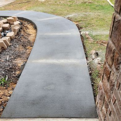 A concrete walkway is being built next to a brick wall