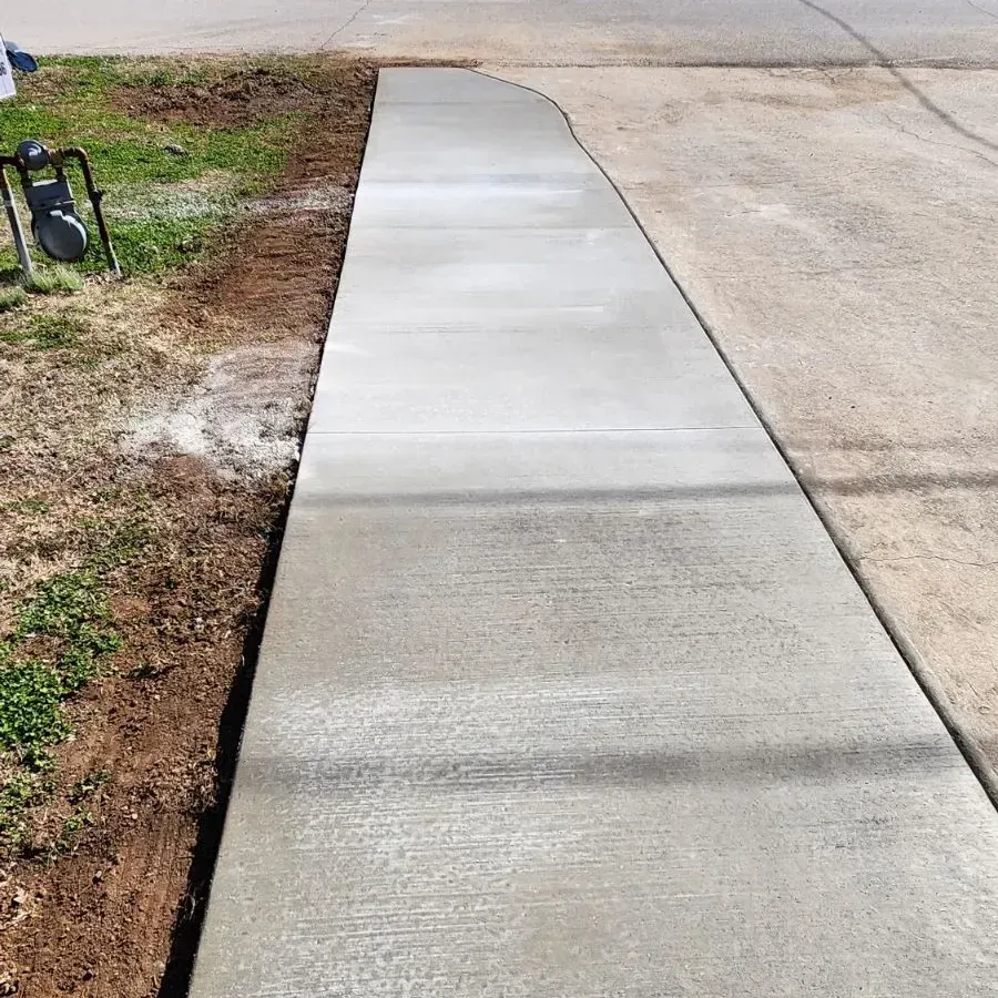 A concrete sidewalk is being built next to a grassy area