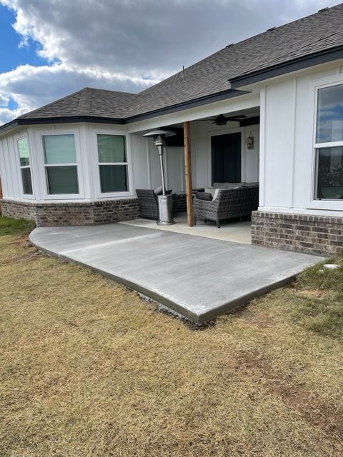 A large white house with a concrete patio in front of it.