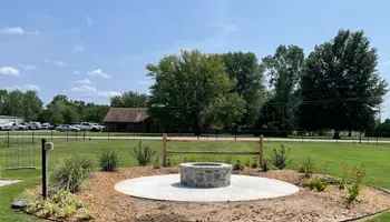 A fire pit is sitting in the middle of a grassy field.